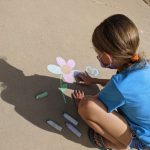 Girl drawing flower with chalk